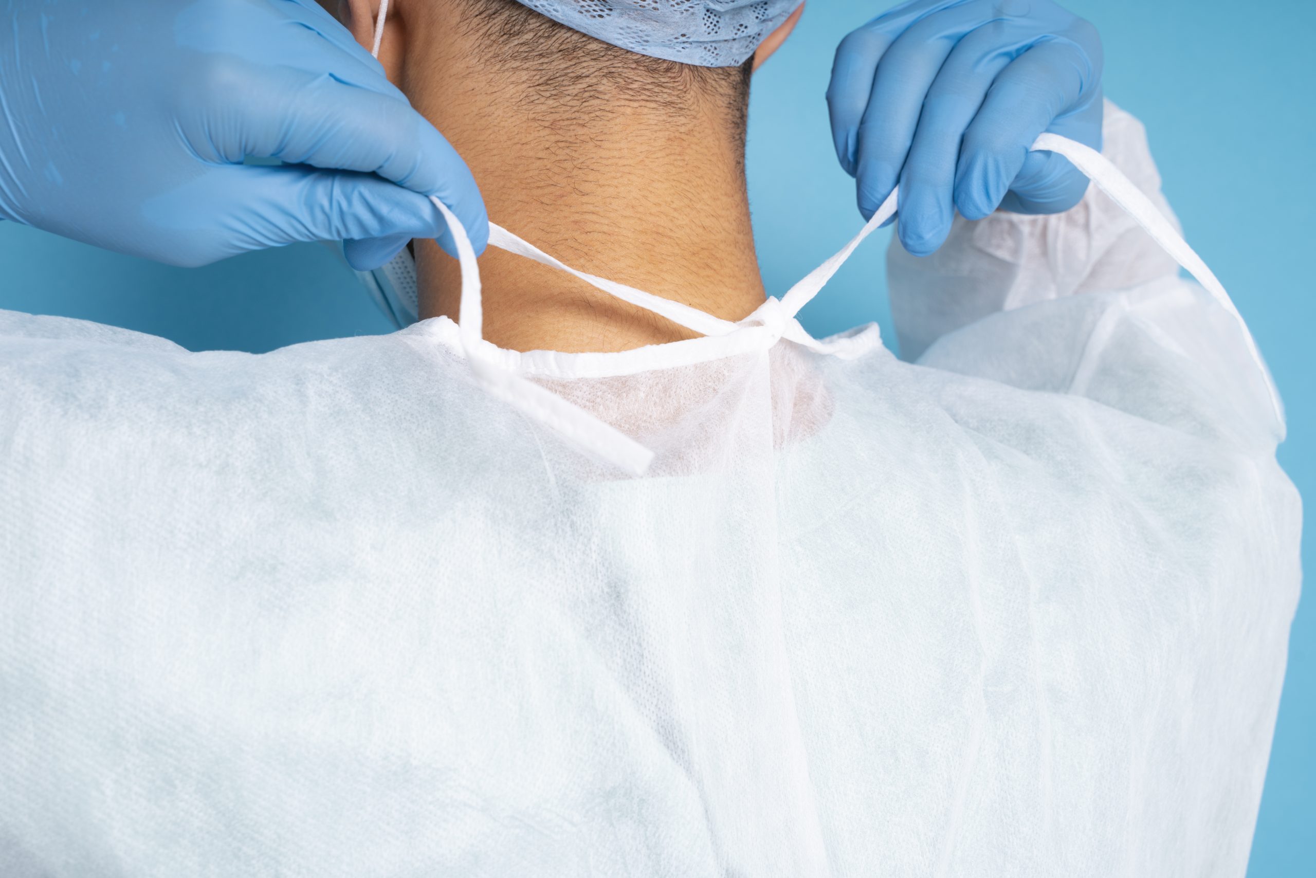 doctor-tying-medical-gown-side-view dermochirurgia